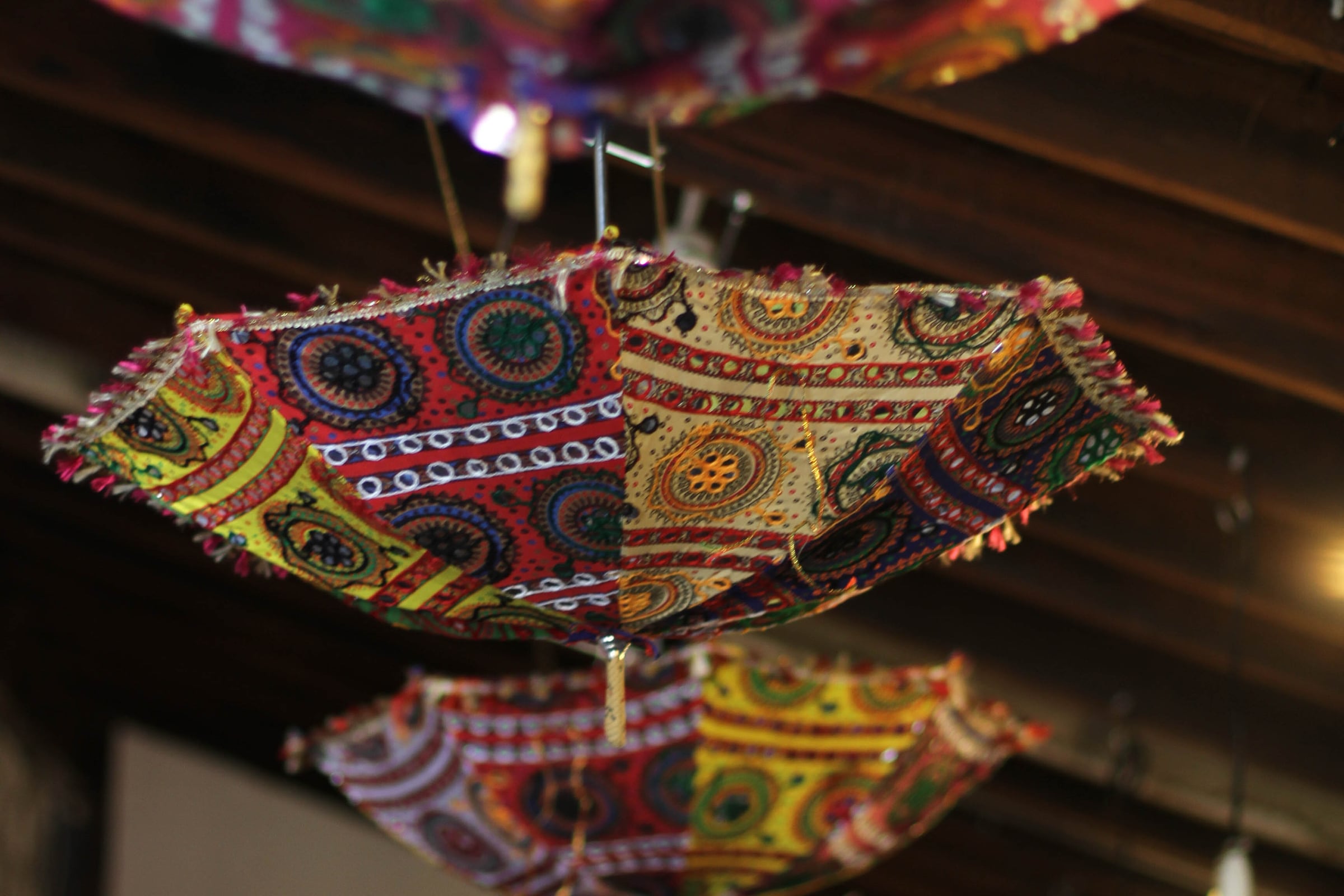 Embroidered mirror-work parasols hanging from the timber ceiling at Maiaveda