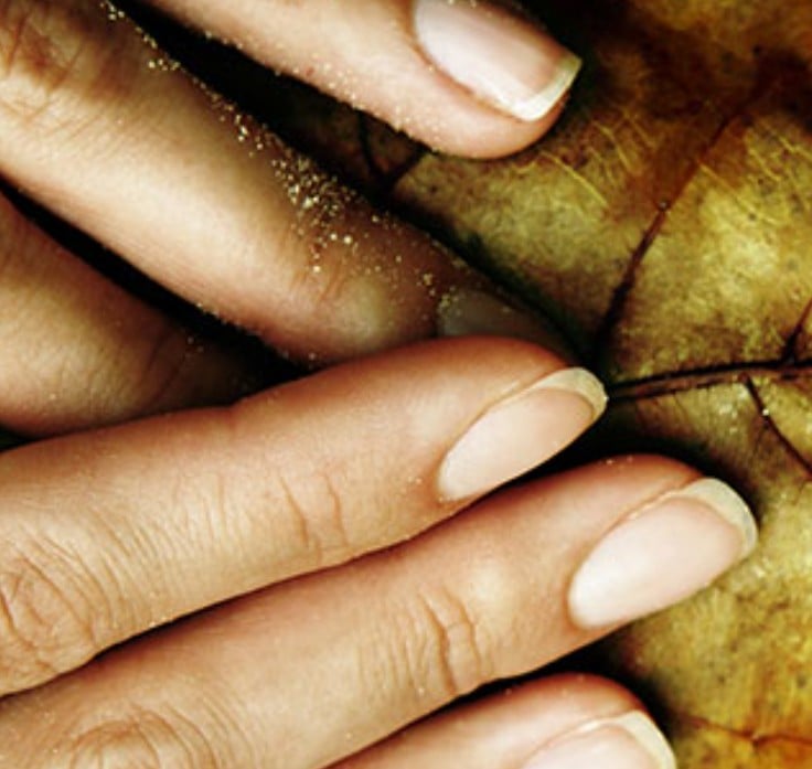 Fingertips resting on a golden leaf