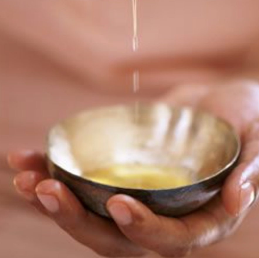 Warm oil dripping into a small bowl held in two hands