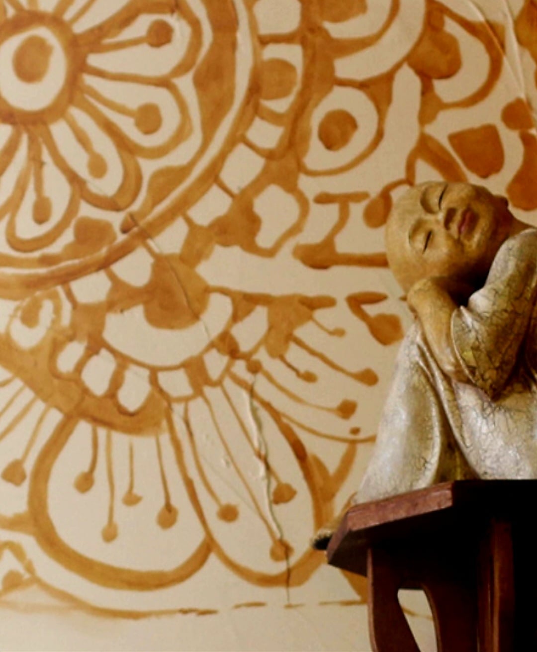 A sleeping Buddha against a painted mandala wall