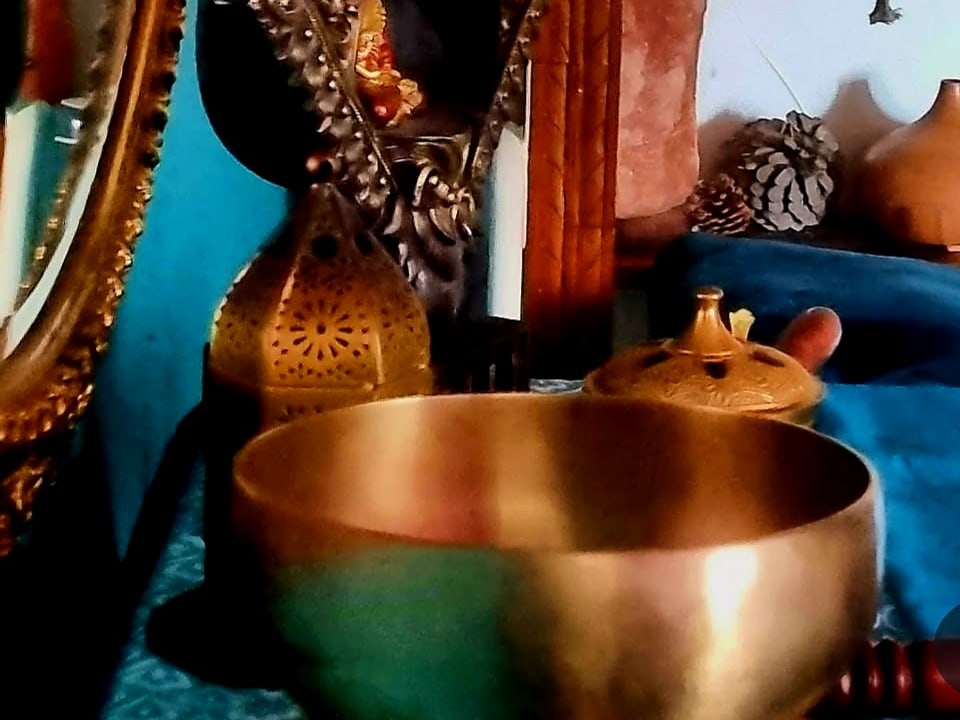 A brass singing bowl in a treatment room, a gilt mirror on the wall beside it