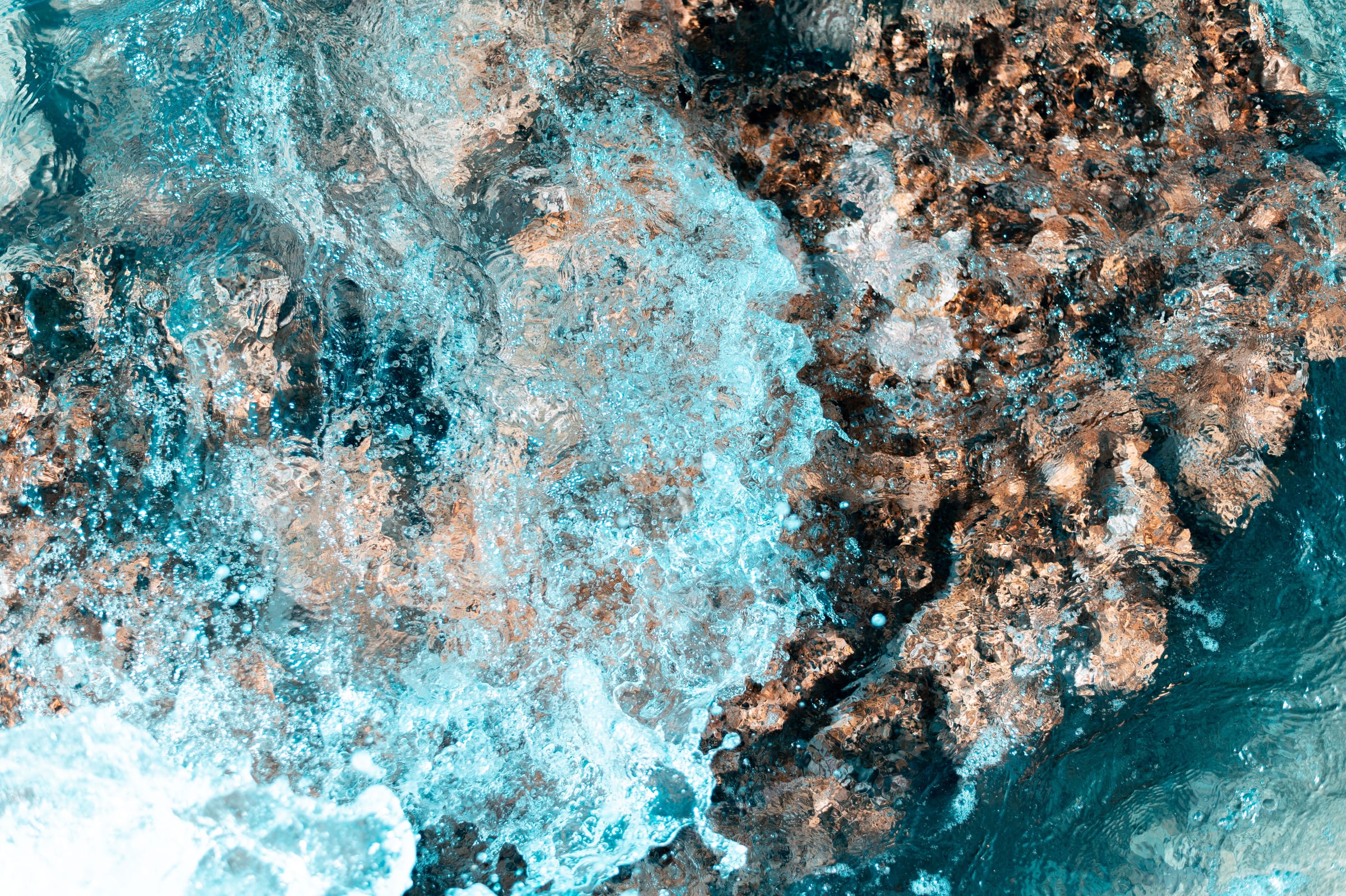 Turquoise water foaming over rock, from above