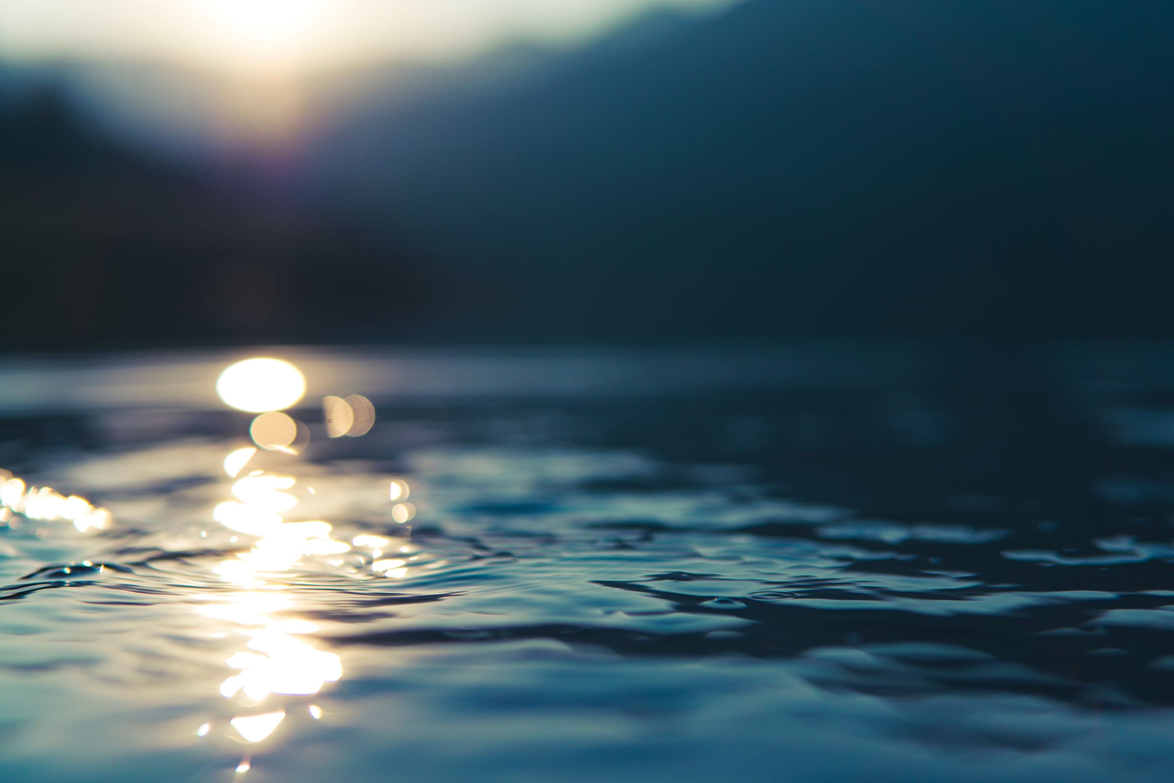 Low sun glinting on dark lake water