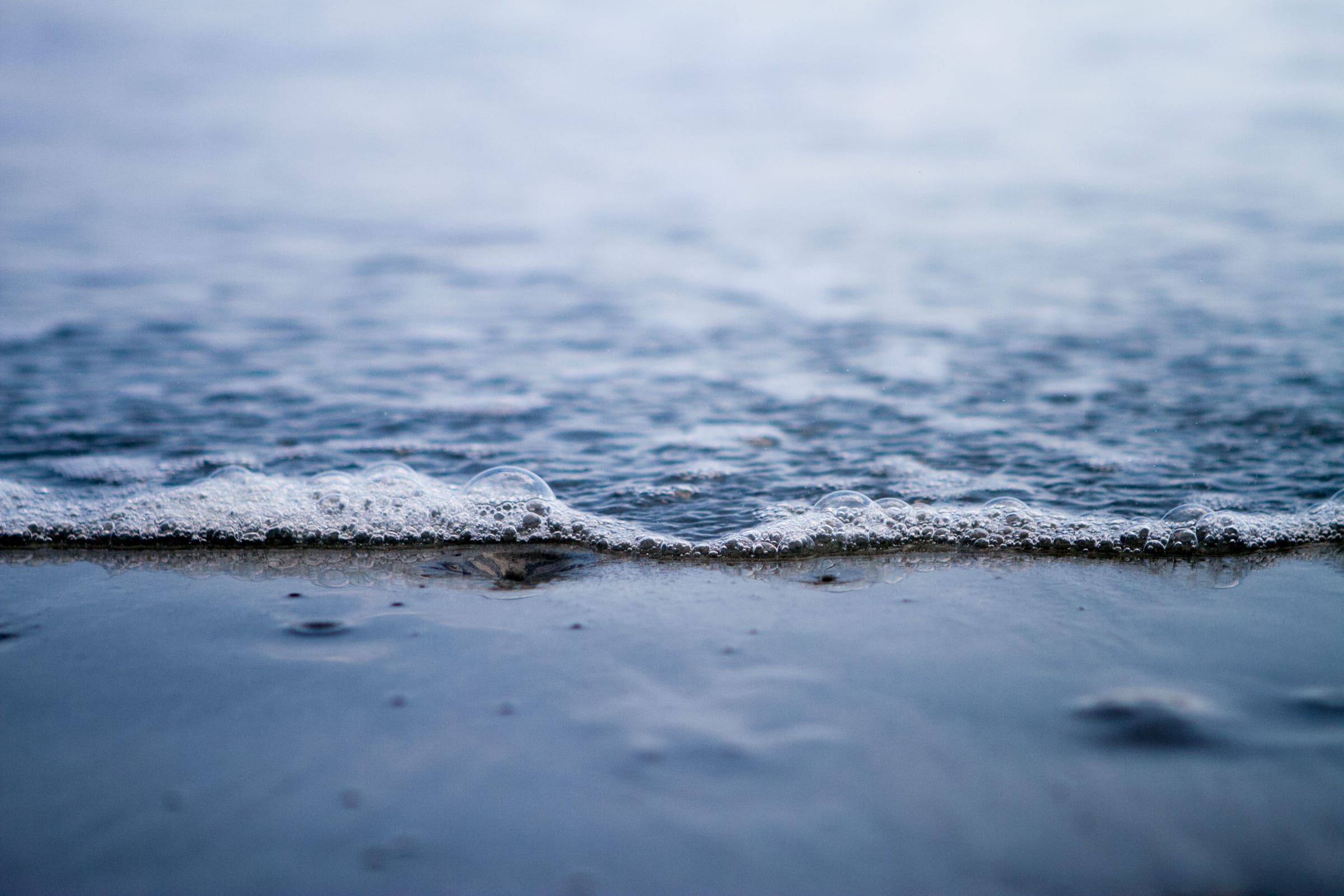 A small wave running onto a grey-blue shore