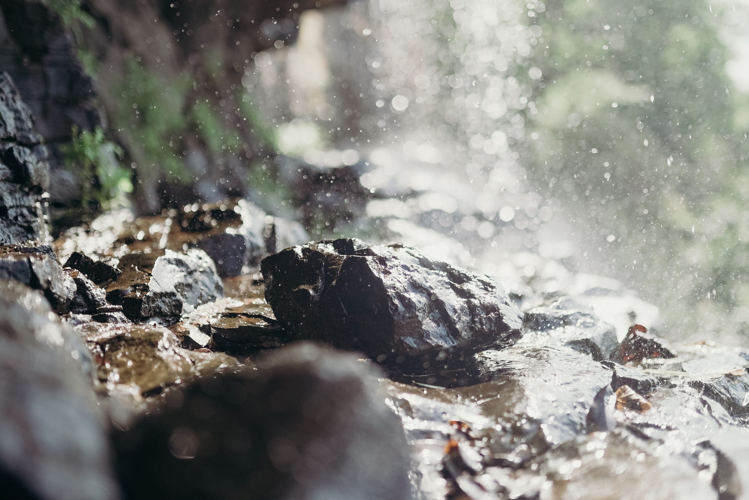 Spray from a waterfall over dark rocks